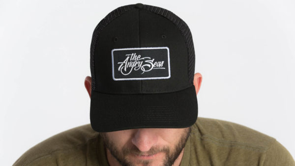 Product: "Signature Script" Snapback Hat // Description: Semi-Curved Bill mesh snapback hat with woven label appliqué // Color: Black on Black // Brand: The Angry Seas Clothing