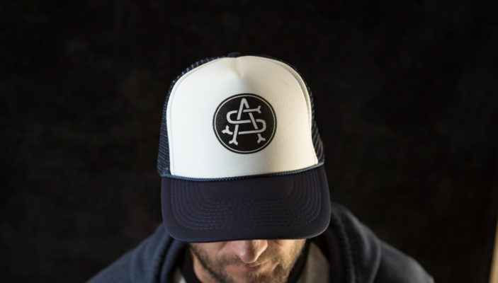 Product: "Monogram" Trucker Hat // Description:  Foam Trucker mesh snapback hat with screen-printed logo // Color: Blue // Brand: The Angry Seas Clothing